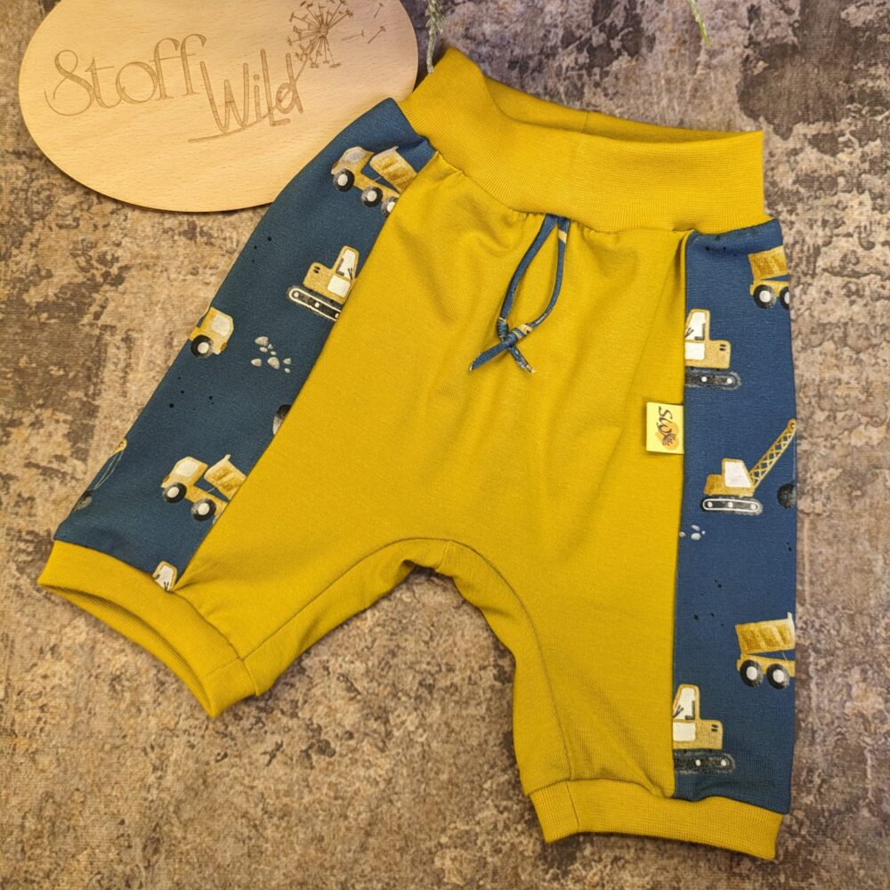 kurze Hose für Babys aus Jersey mit Bagger-Muster und ockergelber, weicher Viskose. Vorne 2 Fake-Bindebänder. Seitlich Kontraststreifen mit dem Bagger-Jersey in blau